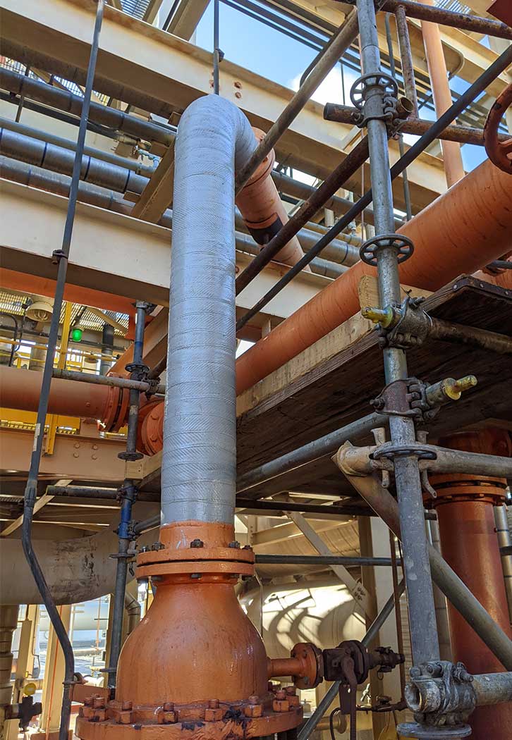 Factory with exposed pipes, one pipe repaired with Carbon material